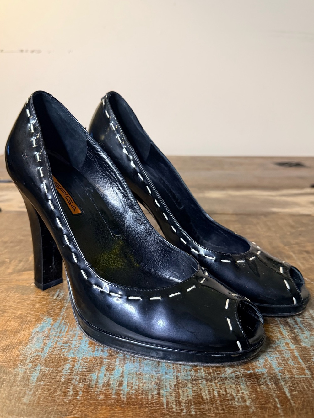 Black patent leather Via Spiga peep toe pumps featuring white contrast stitching